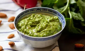 Pesto z liści rzodkiewki, z migdałami i świeżymi ziołami, w miseczce z niebieskim wzorem.