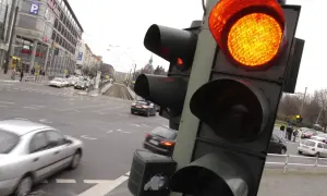 Pomarańczowe światło na sygnalizatorze drogowym. Ruch uliczny w mieście, samochody czekają na zmianę świateł.