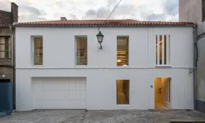 Fachada moderna con pintura al pliolite, puerta de garaje, ventanas y entrada iluminada.