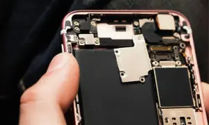Wymiana baterii w iPhone 11: widok wnętrza telefonu z dużą czarną baterią i elementami płyty głównej.