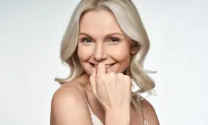 Uśmiechnięta kobieta z blond włosami, która lekko przygryza palec. Czy to fiksacja?