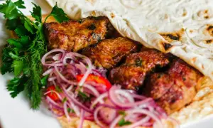 Kebab z mięsem, cebulą i ziołami zawinięty w placek.