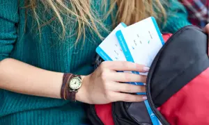 Karta pokładowa Wizzair jak wydrukować? Kobieta wkłada do plecaka dwie karty pokładowe.