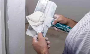 Application d'enduit de lissage sur un mur. Le temps de séchage est crucial avant le ponçage pour un fini parfait.