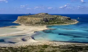 Malownicza zatoka z turkusową wodą i piaszczystą plażą, otoczona skalistymi klifami. To raj dla miłośników przyrody, ukazujący walory przyrodnicze Grecji.