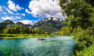Flöße auf einem türkisfarbenen Fluss vor bewaldeten Bergen. Ein idyllisches Bild für Ausflugsziele Polen.