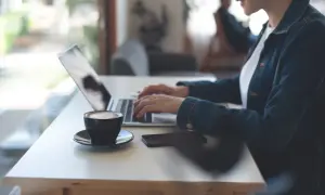 Kobieta pracuje zdalnie przy laptopie, popijając kawę. Nowy kodeks pracy reguluje takie formy zatrudnienia.