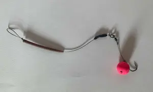Ein **hinged stiff rig** mit einem pinken Pop-up Boilie und einem Haken.