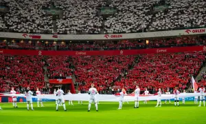 Piłkarze z flagą Polski na murawie, kibice tworzą biało-czerwone morze. Polska w rankingu FIFA zajmuje wysokie miejsce, co widać po dumie na trybunach.