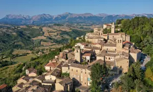 Borgo medievale di Penna San Giovanni, con le sue case in pietra e i tetti in cotto, incastonato tra dolci colline e montagne maestose.