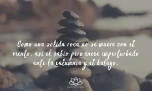 Piedras apiladas con frases de Buda: "Como una sólida roca no se mueve con el viento, así el sabio permanece imperturbado ante la calumnia y el halago.