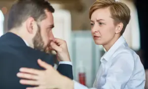Donna consola uomo in lutto, offrendo supporto. Potrebbe essere un permesso per lutto.