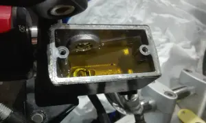 Zbiorniczek płynu hamulcowego w motocyklu z żółtym płynem.