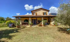 Una casa di campagna con un'auto parcheggiata, piante in vaso e un prato verde. Il momento perfetto quando comprare casa.
