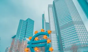 Duży, niebieski znak euro z żółtymi gwiazdami, na tle nowoczesnych wieżowców.