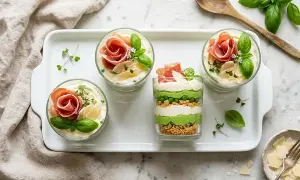 Délicieux tiramisu salé en verrines, garni de fines tranches de jambon, de petits pois et de copeaux de parmesan.