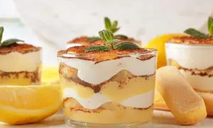 Délicieux tiramisu citron, superposé dans des verres avec des biscuits à la cuillère et des citrons frais.