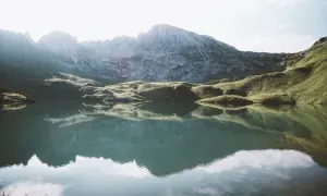 Spokojne jezioro odbija skaliste góry w Niemczech.