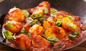 Patate al sugo, un delizioso contorno per carne alla pizzaiola, guarnite con basilico fresco.