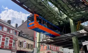 Die orange-blaue Schwebebahn fährt über den Dächern von Wuppertal.
