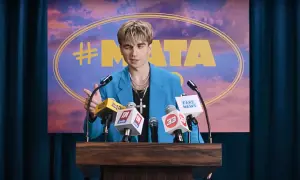 Mata w niebieskiej marynarce przemawia za mównicą z mikrofonami, na tle napisu "#MATA".