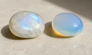 Dos piedras pulidas, una piedra luna iridiscente y otra de un azul lechoso, descansan sobre una superficie clara.