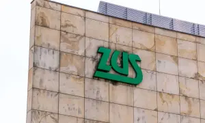 Zielone logo ZUS na beżowej, kamiennej elewacji budynku.