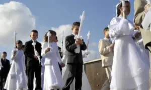 Kinder in festlicher Kleidung, oft weiße Kleider und Anzüge, tragen Kerzen zur Kommunion. Als Gast zur Kommunion zieht man sich festlich, aber dezent an.