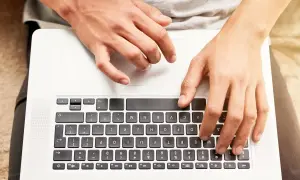 Dłonie na klawiaturze laptopa. Dowiedz się, jak odblokować klawiaturę w laptopie, gdy przestanie reagować.