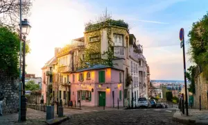 Ein malerisches Viertel in Paris, perfekt für einen Kurztrip. Ein rosa Restaurant mit grünen Fensterläden, umgeben von charmanten Häusern, lädt zum Verweilen ein.