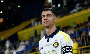 Cristiano Ronaldo w białej koszulce z żółtymi pasami, gotowy do gry. Na ramieniu opaska kapitana.