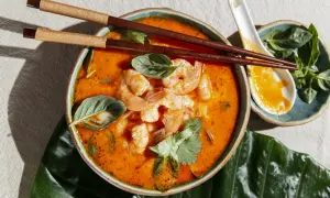Aksamitny, pomarańczowy bulion z krewetkami i ziołami. Aromatyczny tom yam gotowy do spożycia pałeczkami.