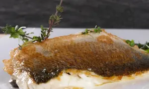 Perfekt gegrillter Wolfsbarsch mit knuspriger Haut und frischen Kräutern, ein Genuss für alle Sinne.