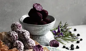 Läckra chokladbollar recept med blåbär och kokos. En skål med mörka bollar och en hög med kokosbollar.