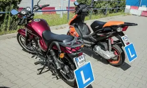 Dwa motorowery z tabliczkami "L" na postoju. Od ilu lat można jeździć motorowerem? Od 14 lat z kartą motorowerową.