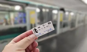 Bilet na metro w Paryżu w dłoni, w tle peron i pociąg.