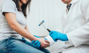 Neurolog bada odruchy pacjentki młoteczkiem neurologicznym.