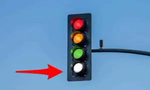 Feux de circulation : rouge, orange, vert et blanc allumés. La flèche rouge indique le feu blanc, une couleur inhabituelle pour les feux de voiture.
