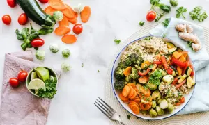 Kolorowa miska pełna warzyw i kaszy, idealna na dietę 1500 kcal. Obok świeże pomidory, cukinia i marchewka.