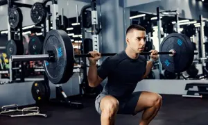 Un homme fait un squat avec une barre chargée, un exercice clé pour un programme musculation prise de masse.
