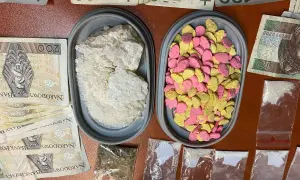 Molly w proszku i pigułki w kształcie serc, obok stosów banknotów.