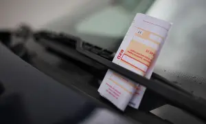 Ein Zettel am Auto wegen Parken liegt unter dem Scheibenwischer.