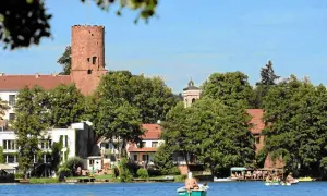 Widok na zamek i jezioro w jednym z malowniczych miast w lubuskim. Ludzie relaksują się na łodziach.