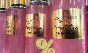 Różowe mgiełki Victoria's Secret Temptation Shimmer z złotymi etykietami i złotym symbolem procentu.