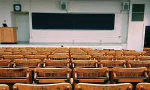 Aula vacía con asientos de madera y pizarra. Un profesor podría hablar aquí, pero para explicar la diferencia entre speak y talk, necesitaría a los estudiantes.