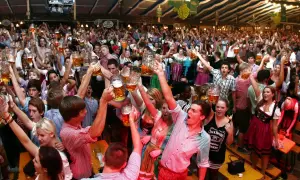 Menschen jubeln und stoßen mit Bierkrügen an auf dem Volksfest Freising.