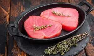 Deux beaux pavés de thon rouge cru, ornés de brins de thym frais, prêts pour une recette savoureuse.