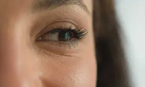 Gros plan sur un œil marron, cils longs et recourbés. Une étape maquillage yeux réussie, le regard est intense.