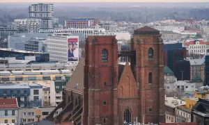 Widok na ceglany kościół garnizonowy we Wrocławiu, otoczony nowoczesną zabudową miejską.