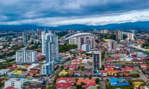 Vy över San José, Costa Rica, med moderna skyskrapor och färgglada hus under en molnig himmel.